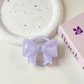 Detail view of a purple bow-shaped magnetic phone grip on a white ceramic tray - Light Purple