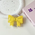 Close-up of yellow resin bow MagSafe phone grip on a white ceramic tray setup - Dark Yellow