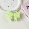 Detail of light green bow phone grip on a white ceramic tray with soft aesthetic lighting - Fluorescent Green