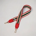 Close-up of adjustable striped webbing strap with red leather ends and gold metal hooks - Red