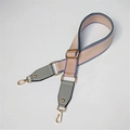 Detail eines verstellbaren rosa-beigen Taschenriemens mit goldenen Karabinerverschlüssen - Grau