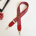 Vue macro de la bandoulière réglable en nylon rouge avec rayures et crochets dorés - Fermoir en Argent / Rouge