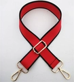 Macro shot of durable red and black woven canvas bag strap with golden metal lobster clasps - Red