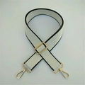 Close-up of beige woven replacement bag strap with black edges and gold metal hardware - White