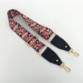 Close-up of ethnic style woven bag strap with colorful geometric patterns and gold clips - Radiant