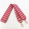 Close-up of a wide red and white houndstooth bag strap with gold metal lobster clasps - Red