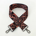 Close-up of geometric jacquard shoulder strap with gunmetal swivel hooks and slider - Black Brown Pattern Gunmetal Buckle