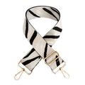Detail view of zebra pattern nylon bag strap with adjustable gold metal hardware - Beige-Black White
