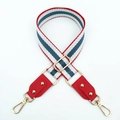 Close-up of red, white, and blue striped bag strap with gold metal buckle and leather ends - Blue Red + Red Leather