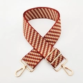 Close-up of a 5cm wide red and yellow geometric jacquard strap with gold metal hardware - Red Brown