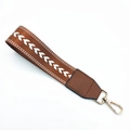 Detail of woven wrist strap with white V-patterns, brown leather and gold lobster clasp - Brown