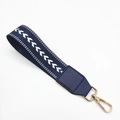 Macro shot of navy woven canvas wristlet strap with white arrows and gold metal clasp - Navy Blue