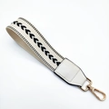 Close-up of wide woven wristlet strap with chevron pattern and gold lobster clasp - Off White