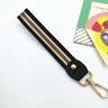 Close-up of woven wrist strap with red and green stripes and gold metal hardware - Retro Black Stripes