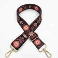 Close-up of ethnic floral embroidery on a black wide bag strap with gold metal hooks - Lotus