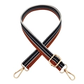 Close-up of geometric orange and black woven bag strap with adjustable gold metal buckle - Black Orange