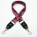 Close-up of pink floral pattern bag strap with gold rivets and lobster clasps - Rose Red Background Flowers + Black Leather