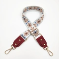 Detail of adjustable floral embroidery strap with golden rivets and metal swivel hooks - White & Brown Flowers + Wine Red Leather