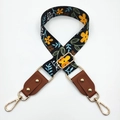 Close-up of floral print bag strap with gold rivets and leather connectors - Black Yellow Flower + Brown Leather