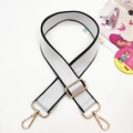 Detail of adjustable wide nylon shoulder strap with contrast black trim and gold hardware - White With Black Edges