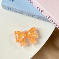 Close-up of orange bow phone grip with heart-shaped sequins on a desk background - Orange Sugar Heart (Large Bow Stand)
