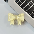 Close-up of a pale yellow resin glitter bow cell phone socket stand on a gray surface - Large Bow Grip-Dot Glitter-Light Yellow