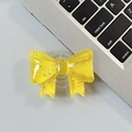 Close-up of a glittery yellow bow-shaped collapsible phone grip on a grey desk - Large Bow Grip-Dot Glitter-Dark Yellow