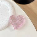 Gros plan d'un support de téléphone cœur à paillettes roses sur plateau terrazzo - Grand cœur tordu - Points pailletés / Rose transparent