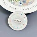 Macro detail of handmade phone grip with iridescent shell texture and colorful rhinestones - Silver Badge