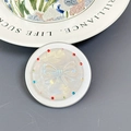 Close-up of pearl bow phone socket with colorful rhinestones on a decorative ceramic plate - Aurora Bowtie