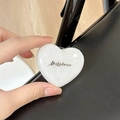 Dettaglio macro del supporto magnetico a cuore per telefono con glitter e logo in metallo - Cuore Stereo - Glitter Bianco / Stile Supporto Adesivo