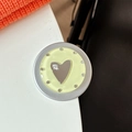 Macro shot of a round yellow phone grip with a silver heart and mine. engraving - Matte Silver Magnetic - Dopamine Small Heart Mirror / Yellow