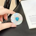 Macro detail of magnetic phone grip featuring heart-shaped blue crystal and iridescent finish - Transparent Stand - Sweetheart / Blue