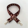 Close-up of adjustable jacquard bag strap with gold-tone metal hooks in reddish brown - Burgundy