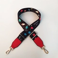 Close-up of adjustable bag strap with colorful space planet patterns and gold metal clips - Red