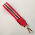 Macro detail of red striped bag strap with premium gold lobster clasp and PU leather end - Red