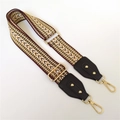 Macro detail of ethnic herringbone wide bag strap with leather ends and gold metal clips - Khaki + Black Leather