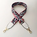 Detail of adjustable wide bag strap with red and black geometric pattern and gold hardware - Black & Red with White Leather