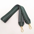 Close-up of geometric embroidered wide shoulder strap with golden metal lobster clasps - Green