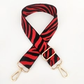 Detail of red and black zebra pattern woven strap with polished gold-tone metal hooks - Red Gold Buckle