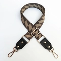 Close-up of geometric pattern crossbody strap with gold metal hooks and leather ends - Dark Green + Black Leather