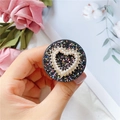 Detail of heart-shaped pearl and rhinestone phone grip on a black glitter base - Hollow Heart / Black