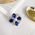 Close-up of sparkling flower phone grip with blue rhinestones and a central pearl - Blue