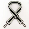 Detailaufnahme des verstellbaren Taschenriemens mit grünem Punktmuster und dunklen Karabinern - Schwarz und Hellgrün Mit Gunmetal-Schnalle