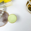 Flat lay of a round cream-colored phone grip with elegant gold trim and pearl accessories - Round Electroplated Stand / Macaron Fluorescent Yellow