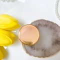 Dettaglio del supporto per telefono rotondo in oro rosa su un sottobicchiere di marmo - Oro Rosa Gemma