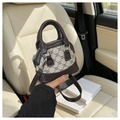 Detail der Canvas-Mini-Muscheltasche mit Monogramm-Muster und Lederbesatz im Auto-Interieur - Kaffee & Khaki