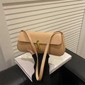 Beige patent leather shoulder bag with gold metal clasp on white book background - Khaki