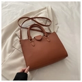 Detailed macro view of the brown lychee texture and light gold buckles on a tote bag - Brown