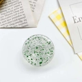 Close-up of circular phone grip featuring green glitter flakes and clear resin finish - Epoxy Gold Foil Round / Green